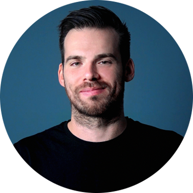 Me with a smirky smile on my face. I have short brown hair and a short beard and I'm wearing a black t-shirt